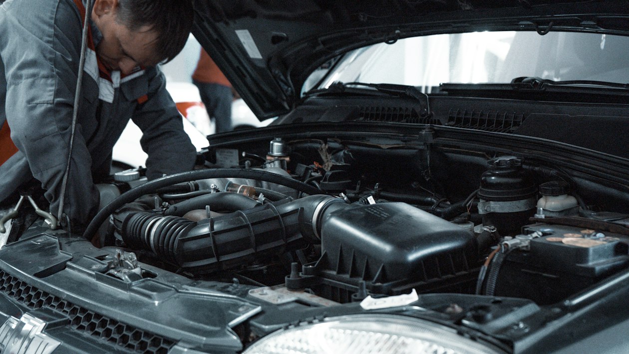 Mécanicien inspectant un compartiment moteur de voiture dans un atelier de réparation automobile
