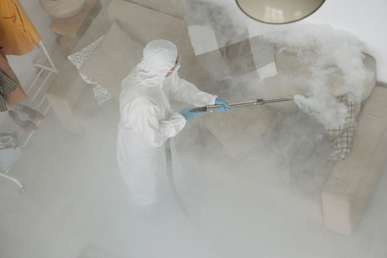 Technicien de lutte antiparasitaire en vêtements de protection traitant un canapé